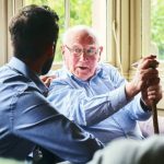 Senior man talking with health visitor during care home visit